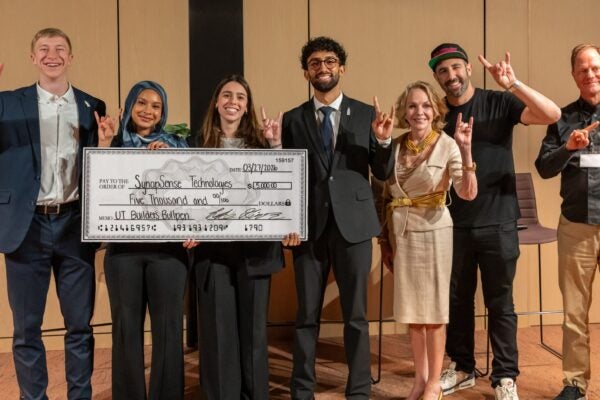 image of students with a check for their winning presentation alongside judge panel