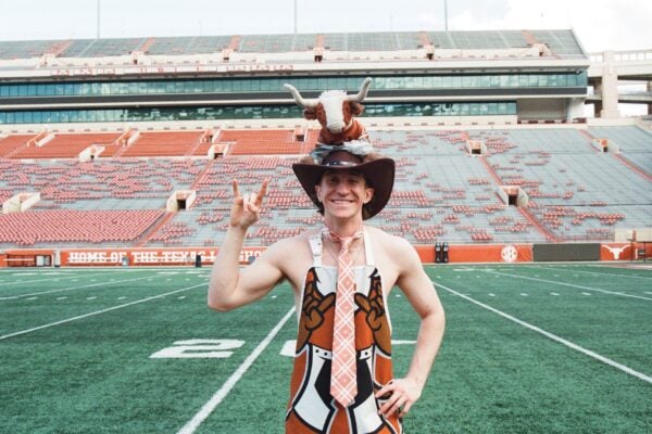 image of a student in the middle of the stadium doing hook 'em