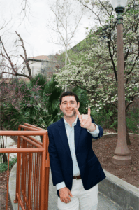 image of a student in a blazer doing the hook 'em sign