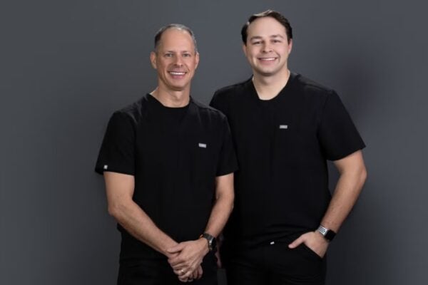 two men in black shirts against grey background