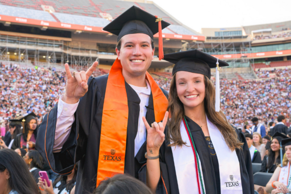 image of two people at commencement holding up hook 'em