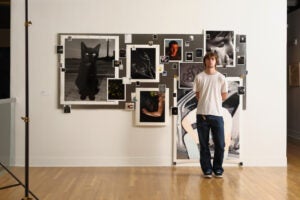 image of a student standing in front of his photographs in a gallery