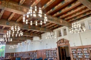 The Hall of Texas, a high ceilinged library room with ornately painted beams, rafters and ceiling and circular chandeliers