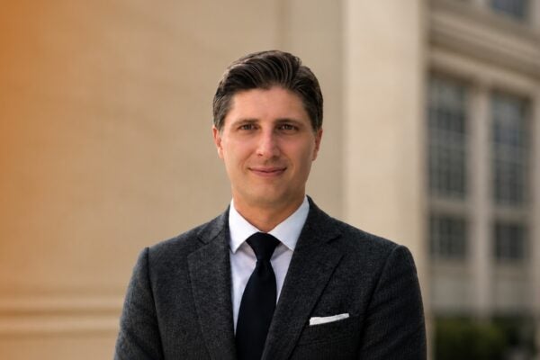 Man in a suit poses in front of a building.
