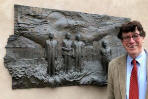 image of a man in front of a bronze picture on a wall