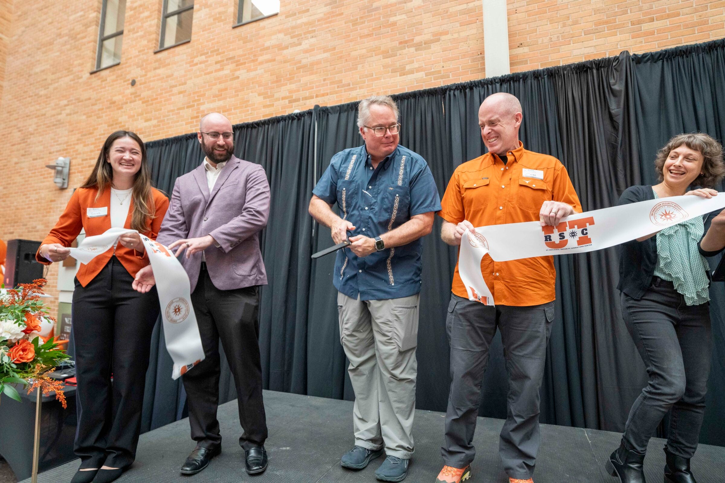 Texas Cyber Command Chief Timothy James “TJ” White cuts the ribbon to celebrate UT-RSOC’s new office alongside staff members.