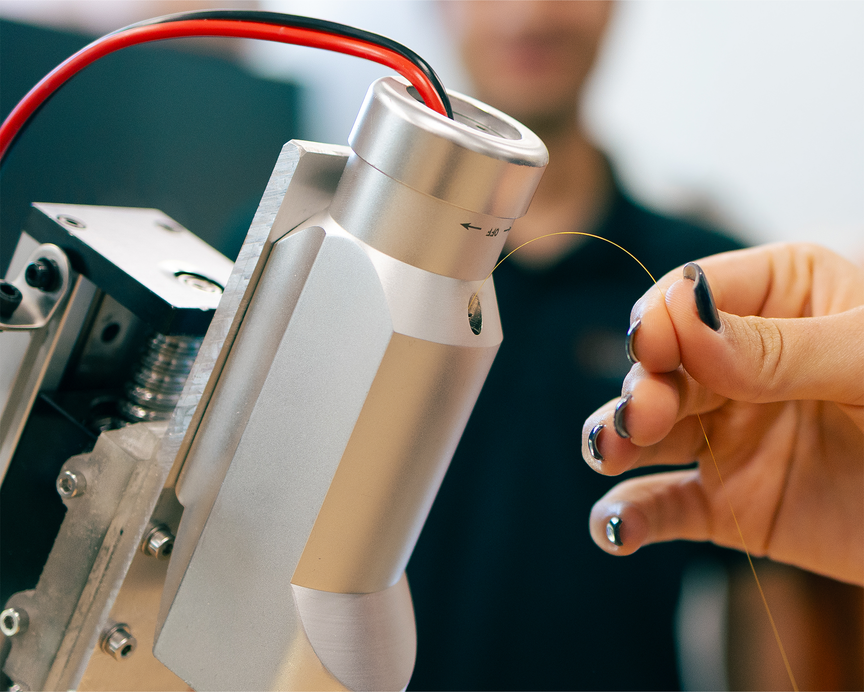 A hand holds a sensing fiber on a robotic device.