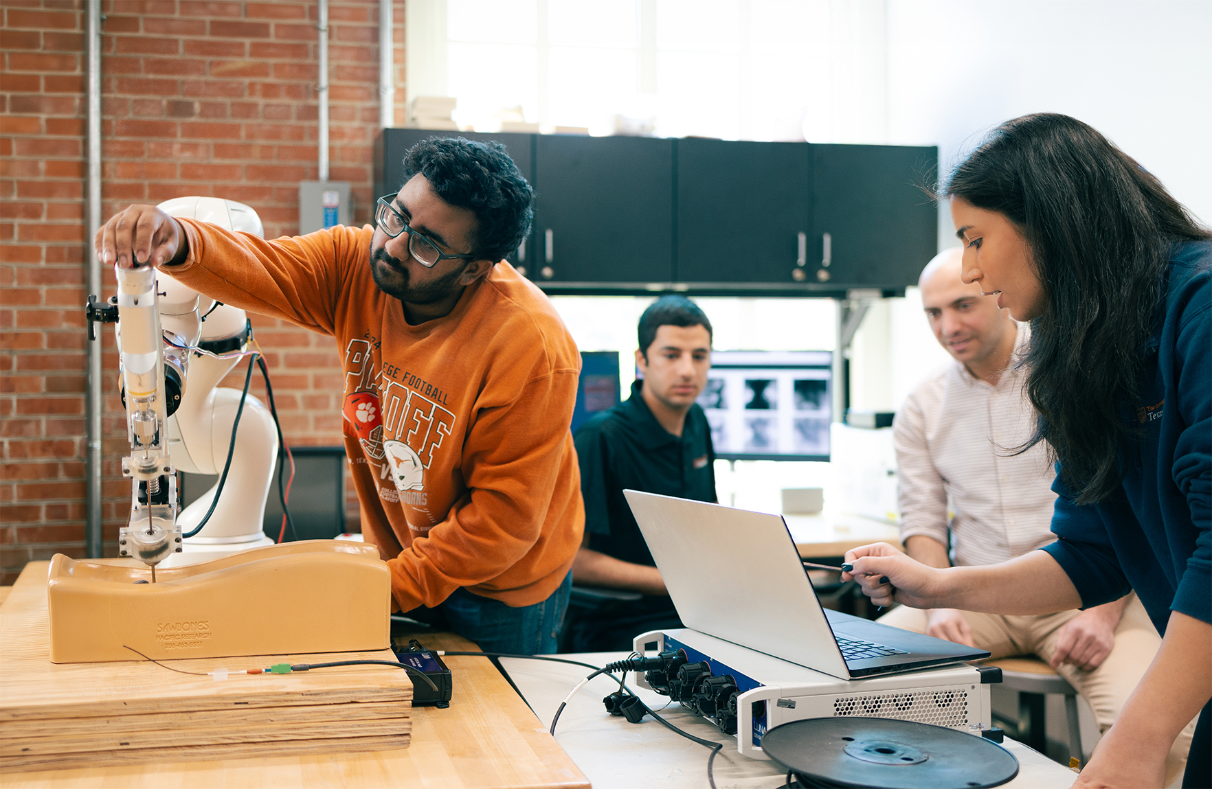 Four researchers work on a robotic device.