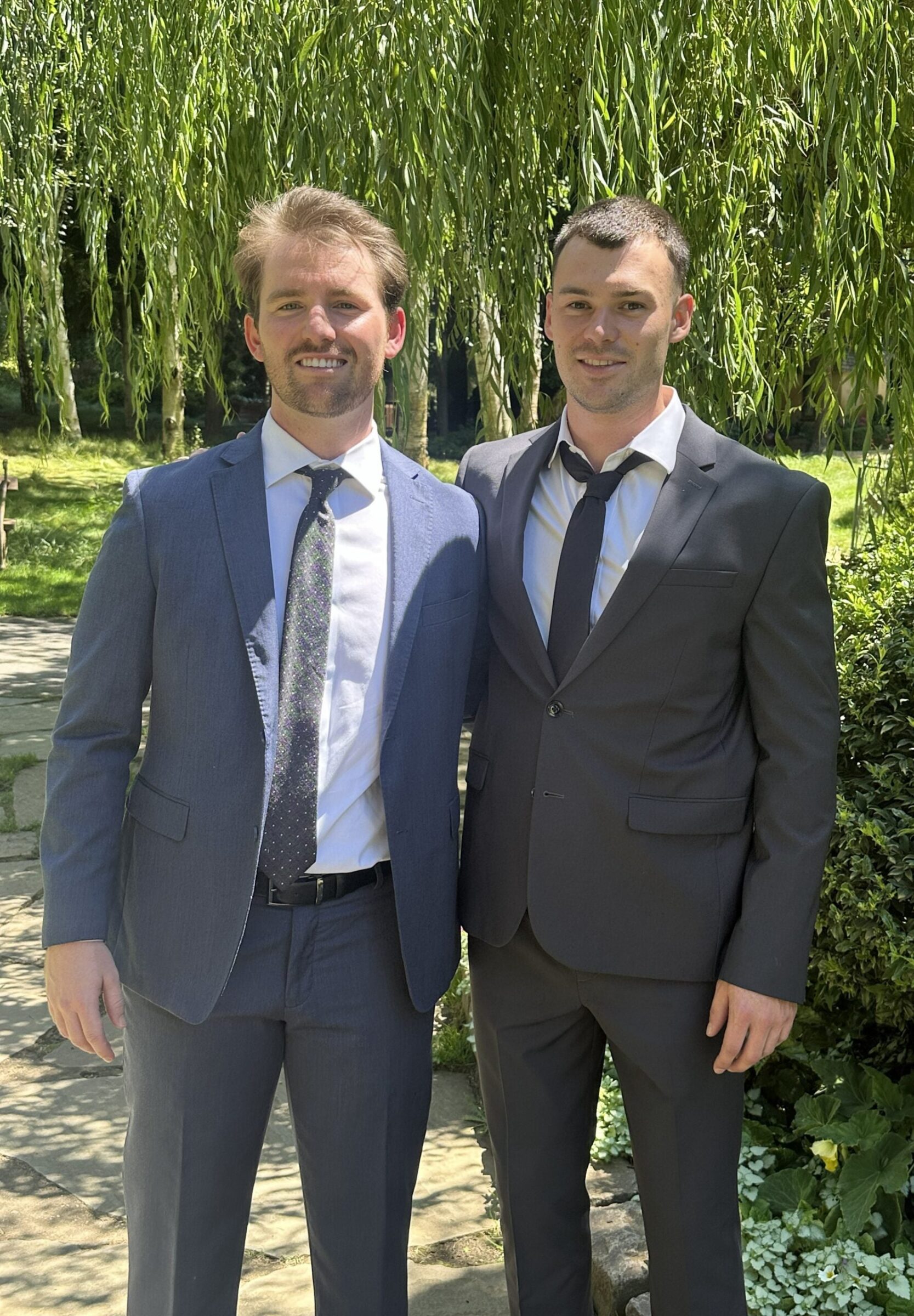 Two men wearing suits smile for a photo.
