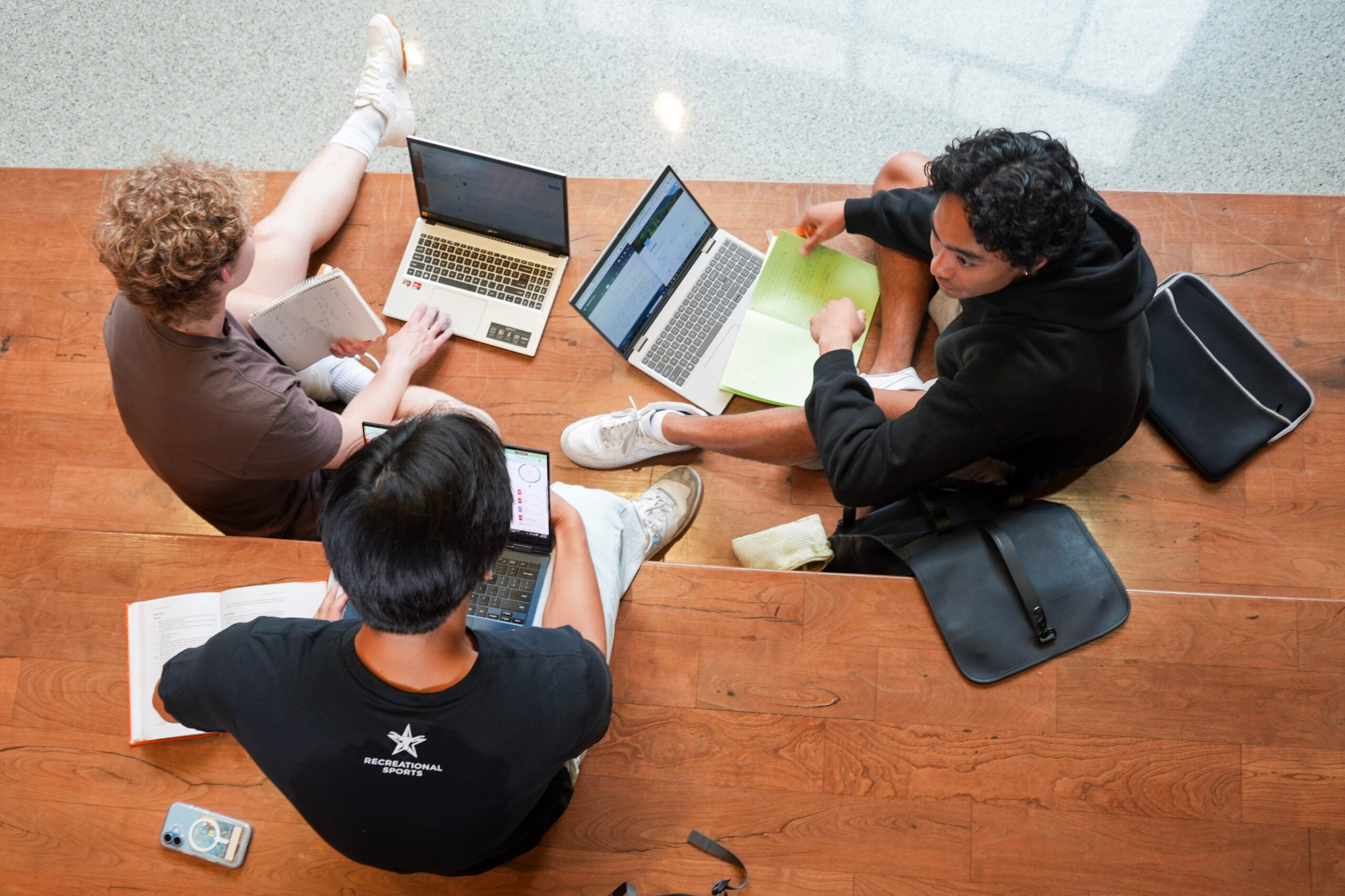 Three students working on their laptops photographed from an above angle.
