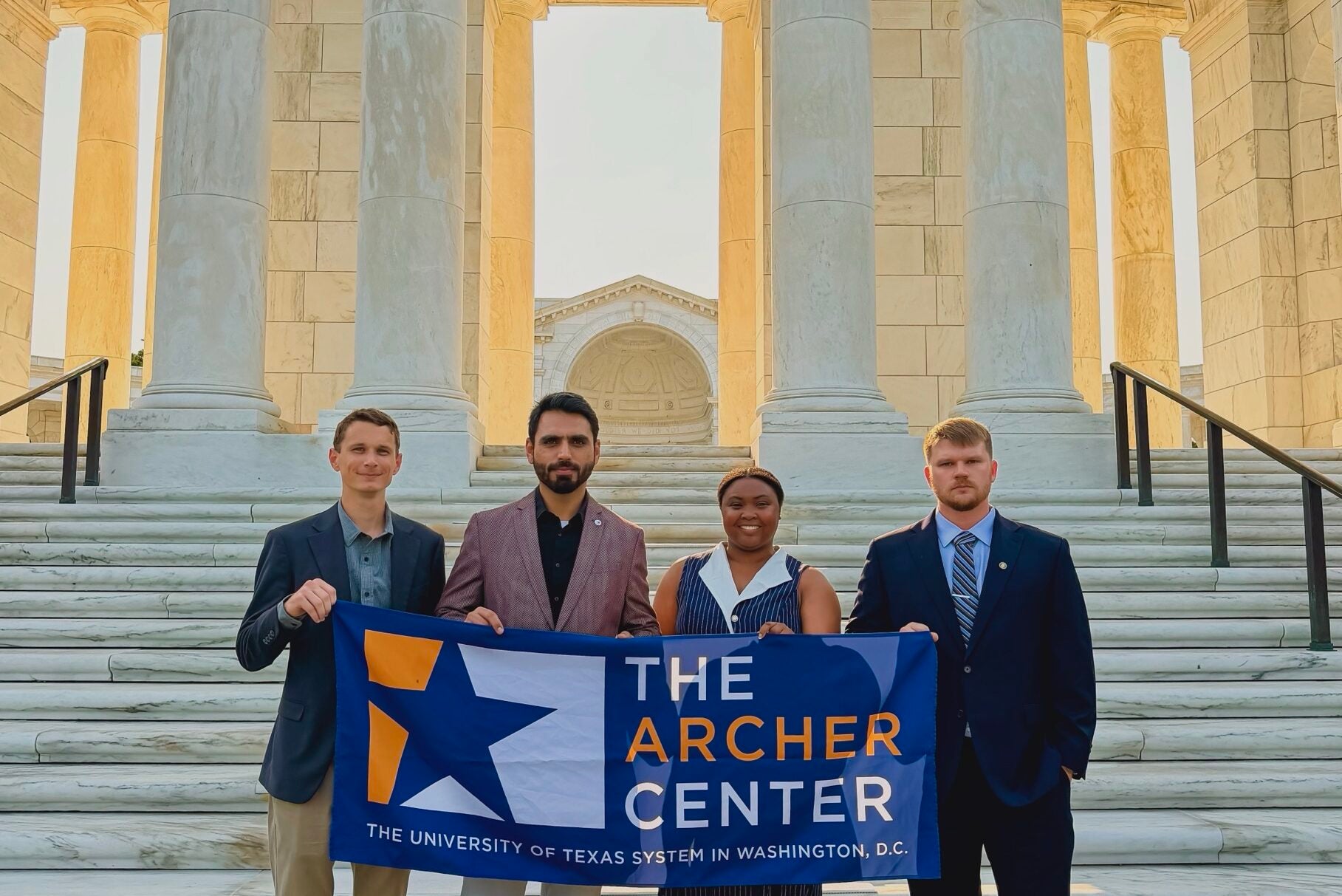 a group of four students holding up a flag that says "the Archer Center"