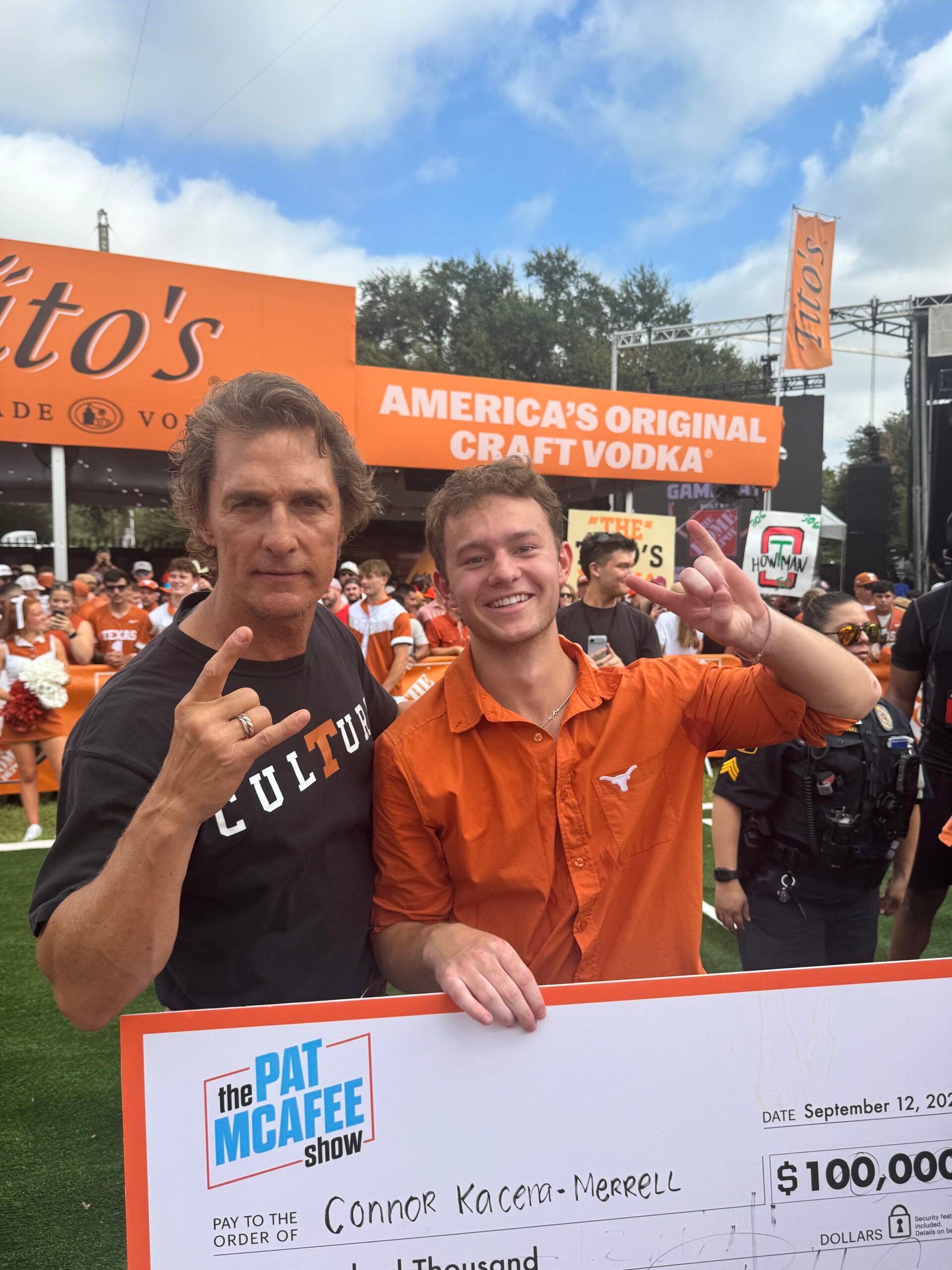 Two men smile while holding a large cardboard check.