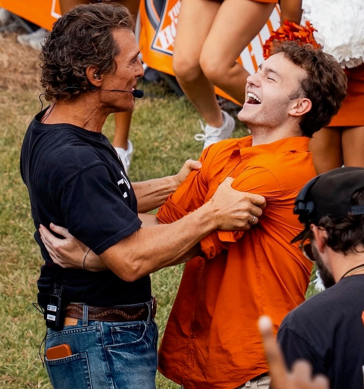 Two men smile at each other as they grip each other's arms.