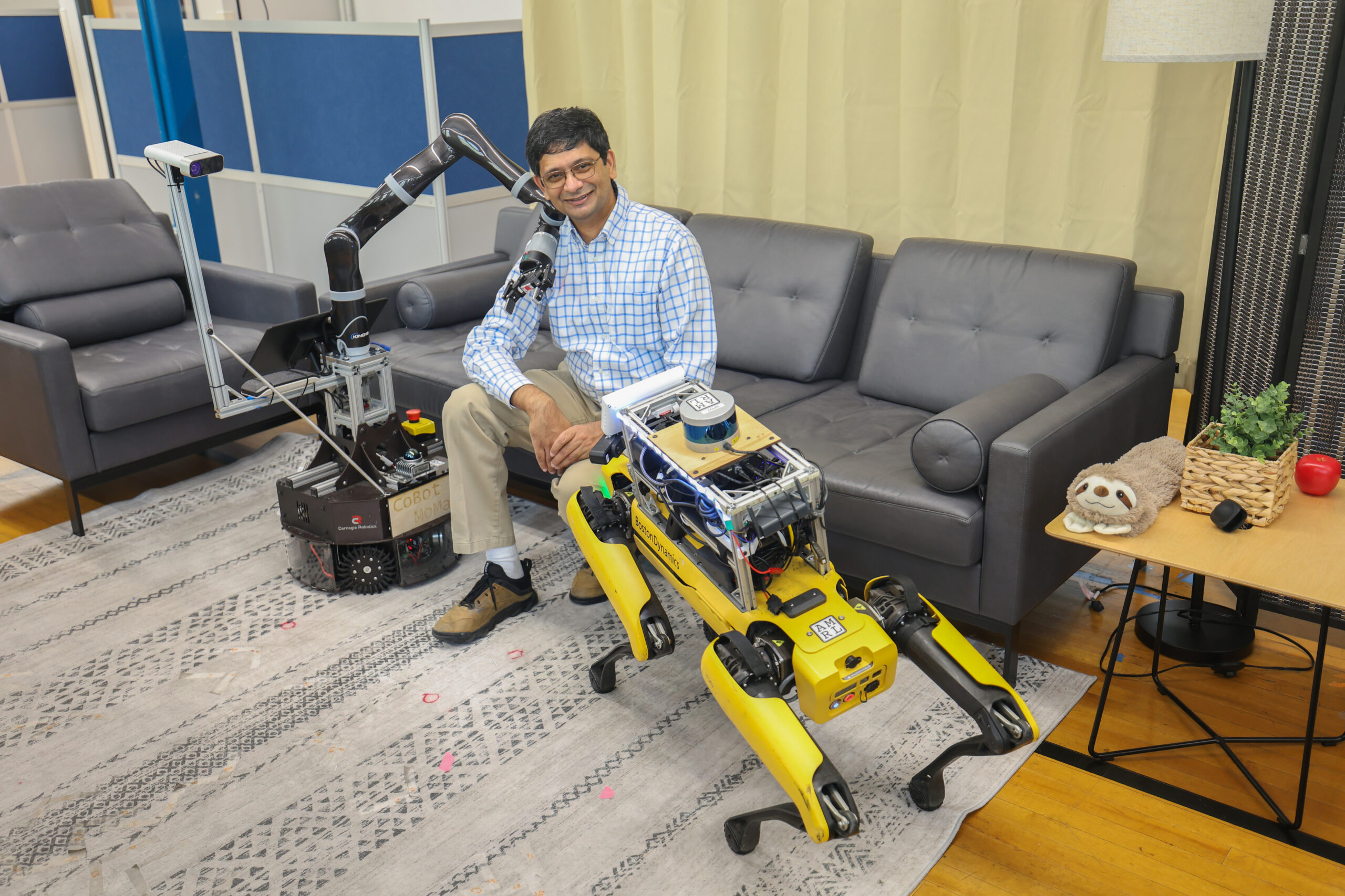 Man sits on sofa with two robots beside him.