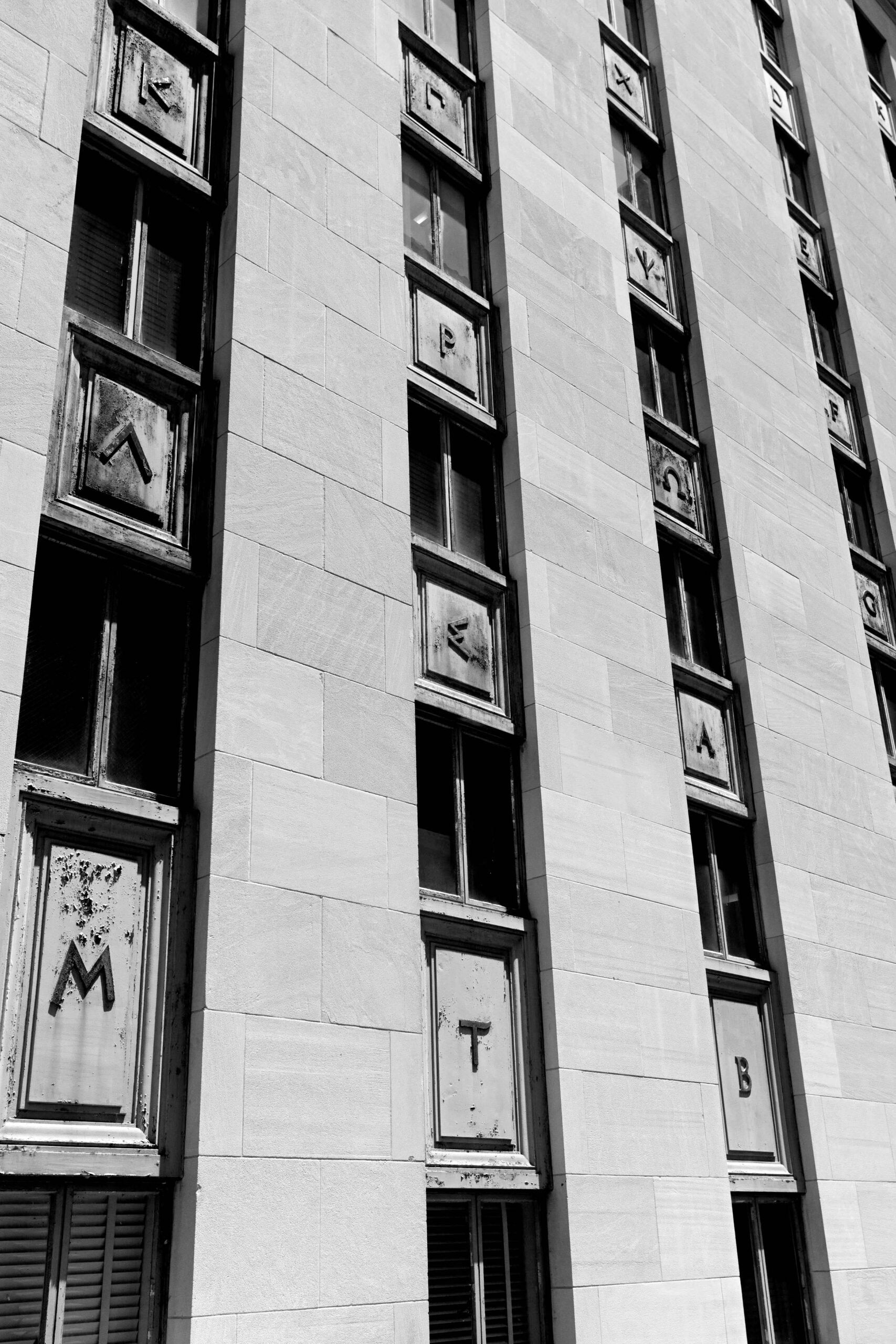 A black and white photo of the UT Tower windows and decorative characters.