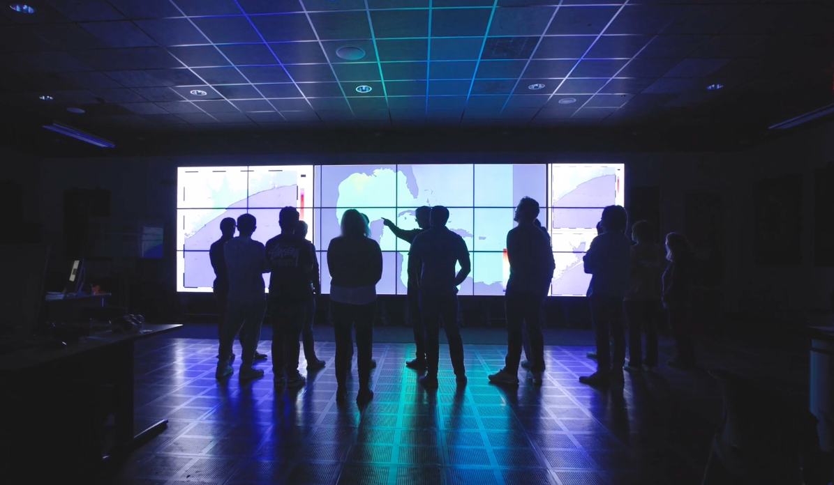 image of a group of people standing in front of a screen with storm info