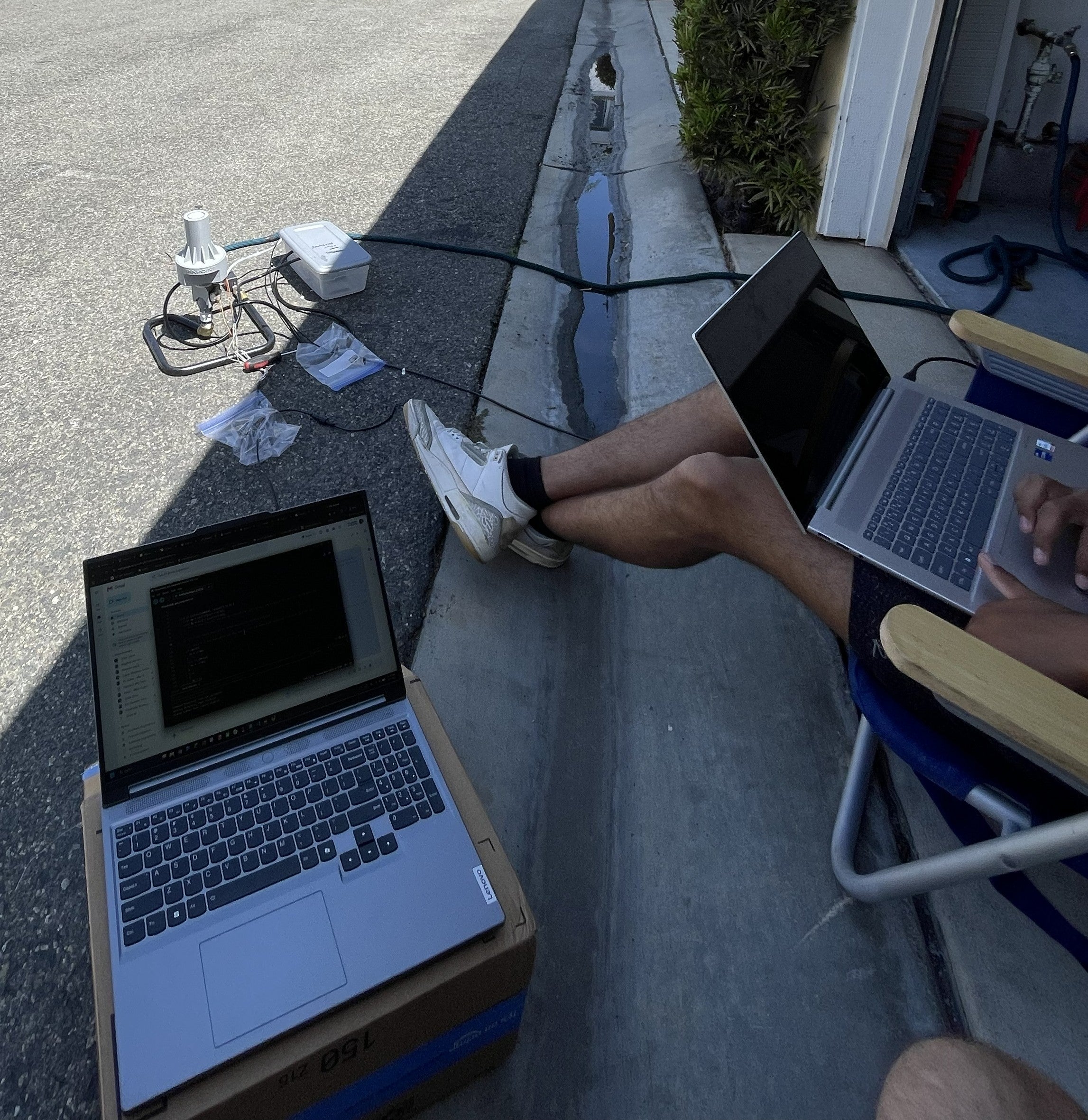 Two people with laptops test a sprinkler system.