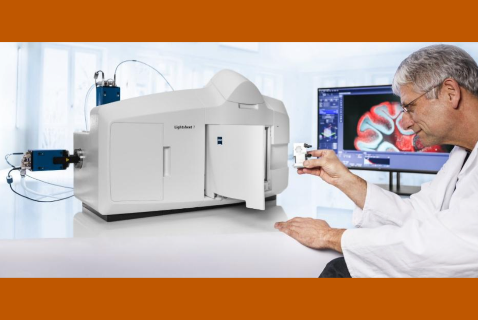 A man wearing a white lab coat inserts a sample into a ZEISS Lightsheet 7 Fluorescence Microscope.